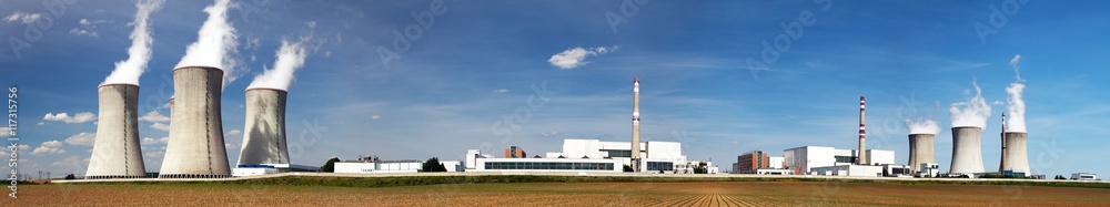 Cooling towers and reactor buildings of a nuclear power plant under a blue sky